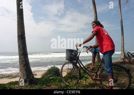 Sri Lanka Lokalmatador sitzt auf seinem Fahrrad schieben und einen Blick auf die Wellen brechen an den Korallenriffen vor der Küste. Sri Lanka. Stockfoto