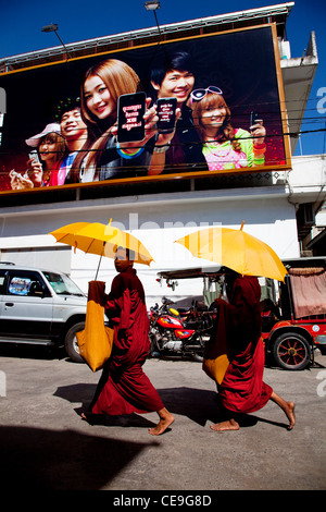 Zwei buddhistische Mönche zu Fuß in den Straßen von Phnom Penh, Kambodscha, Asien unter gigantischen Plakatwand Stockfoto