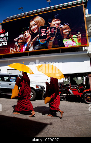 Zwei buddhistische Mönche zu Fuß in den Straßen von Phnom Penh, Kambodscha, Asien unter gigantischen Plakatwand Stockfoto