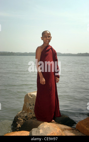 Ein junger Mönch steht vor einem See in der Nähe seines Tempels Klosters Stockfoto