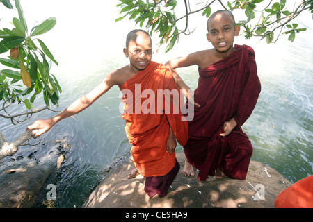 Zwei junge buddhistische Mönche gekleidet in traditionellen Gewändern stehen neben einem See Stockfoto