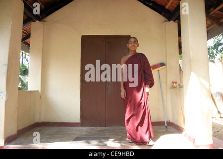 Ein junger Mönch gekleidet in traditionellen orangefarbene Gewänder steht vor seinem Zimmer in einem Kloster in Sri Lanka. Stockfoto