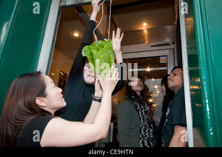 Chinesischen Brauch, hängende Salat in Tür des Restaurants für die Marionette Löwe zusammen mit roten Umschlag mit Geld für Essen gehen Stockfoto