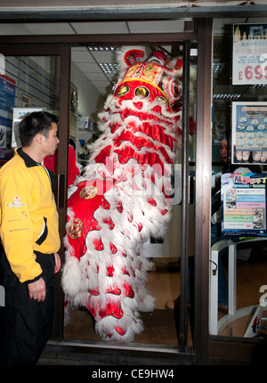 Chinese New Year Tradition wo Löwen Marionette Resta Lebensmittel mit roten Umschlag mit Geld (symbolisiert Glück) gespeist wird Stockfoto