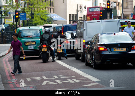 Rückansicht der Motorradfahrer und ein Taxi im Verkehr fahren durch das Zentrum der Londoner City. Stockfoto