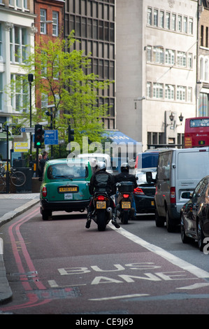 Rückansicht der Motorradfahrer und ein Taxi im Verkehr fahren durch das Zentrum der Londoner City. Stockfoto