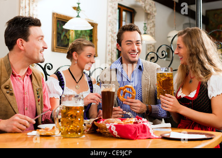 Gruppe von jungen Männern und Frauen in traditionellen bayerischen Tracht mit einem Frühstück mit weißen Weißwurst, Brezel und Bier Stockfoto