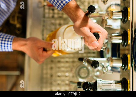 Mann ein Bier vom Hahn auf einem Kegerator im Pub oder Inn zeichnen Stockfoto