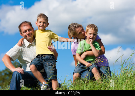 Glückliche Familie (Vater, Mutter und zwei Söhne) im Sommer vor einem blauen Himmel Stockfoto