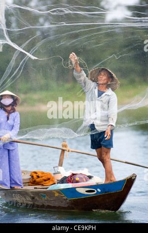 Ein Fischer schwingt seine große gewichteten netto um seinen Kopf und in den Gewässern des Flusses Thu Bon in der Nähe von Hoi an in Vietnam. Stockfoto