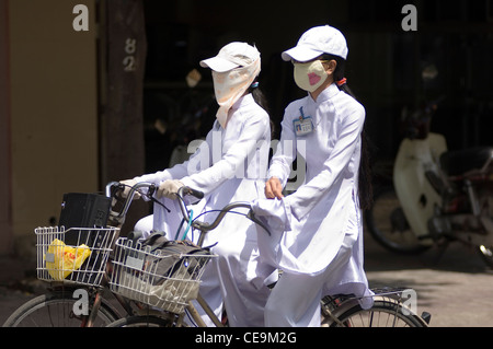 Sekundäre Schulmädchen in Vietnam tragen elegante weiße Chong Sams und versuchen, ihre Gesichter, Arme und Hände gleichermaßen als weiß. Stockfoto