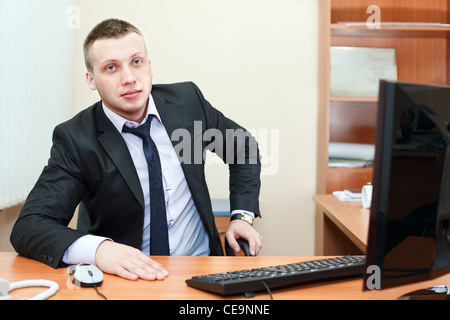 Porträt eines erfolgreichen jungen kaukasischen Geschäftsmann sitzen und arbeiten ein modernes Büro Stockfoto