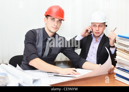 Architekten und Bau-Ingenieur diskutieren Plan im Büroraum. Kaukasische Menschen in Helme Stockfoto