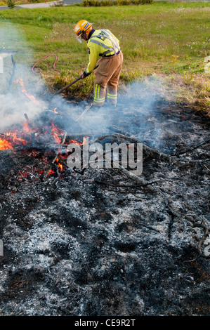 Feuerwehrmann, Feuer mit Schaufel während Übung Außerbetriebnahme. Stockfoto