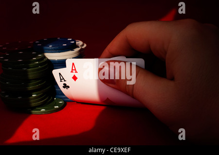 Zwei Asse hoch am roten Tisch mit Chips auf schwarzem Hintergrund Stockfoto