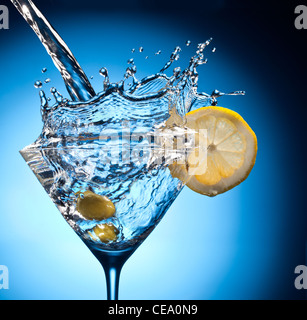 Spritzen von strömenden Martini in das Glas. Objekt auf blauem Grund. Stockfoto