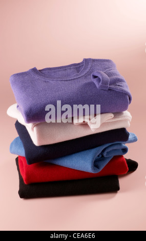 Stillleben-Schuss von fein säuberlich gestapelt bunte Damen Rundhals Pullover auf einem rosa Hintergrund Stockfoto