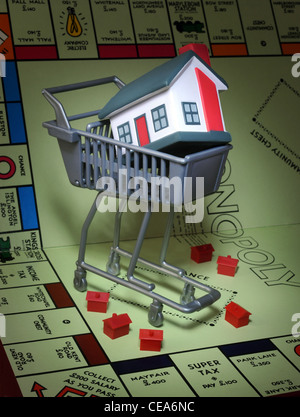 MUSTERHÄUSER AUF MONOPOLY SPIELBRETT MIT SUPERMARKT SHOPPING TROLLEY RE HAUSKUNDEN KAUF IMMOBILIEN MARKT PREISE HÄUSER UK Stockfoto