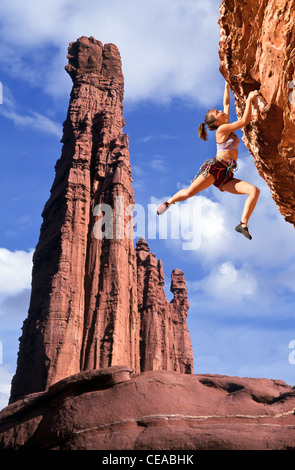 Weibliche Kletterer kämpft, um ihren nächsten Griff am Rande einer anspruchsvollen Klippe zu erreichen. Stockfoto