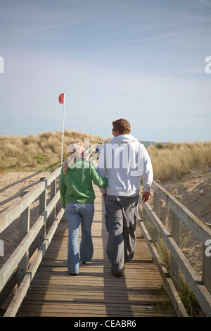 Paar im Urlaub in Barmouth zu Fuß auf einer Brücke in Richtung Strand Stockfoto