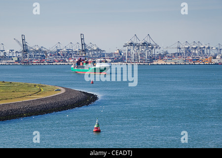 Containerschiff am Fluss mit Industrie und Kräne im Hintergrund Stockfoto