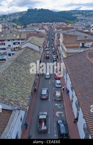 Eine Luftaufnahme von einer Straße in Quito, Ecuador mit roten Ziegeldächern, Autos und Fussgänger in der Straße und fernen Bergen. Stockfoto