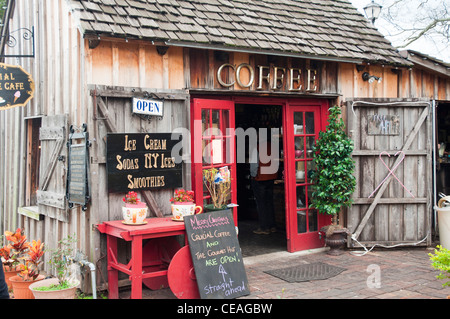Romantisches gemütliches hölzernes Kaffeehaus in St Augustine, Florida, mit rustikalen Schildern, roten Türen und Sitzbereich im Freien auf einem Backsteinpfad. Stockfoto