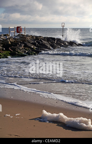 Wellen brechen in der Sonne und an einem kalten Wintertag im Dezember auf eine Buhne in Bournemouth spritzt Stockfoto