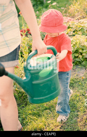 Junges Mädchen hilft ihrer Mutter im Garten Stockfoto