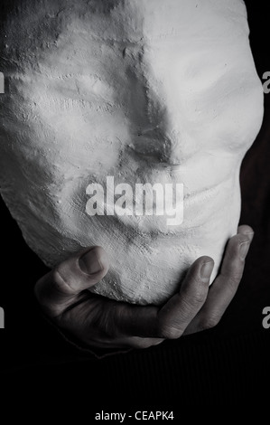 Hand, die eine lächelnde Maske Stockfoto