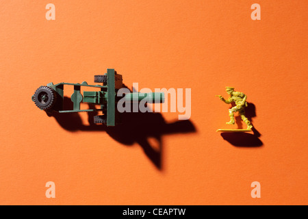 Spielzeugsoldat und Canon auf orangem Hintergrund Stockfoto