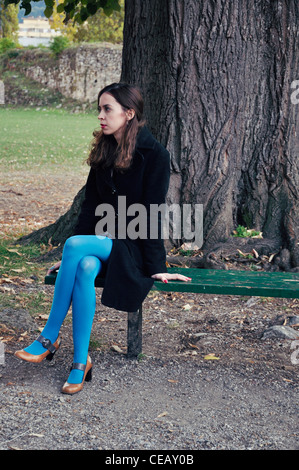 Junge Frau allein auf Park Bank im Freien sitzen Stockfoto