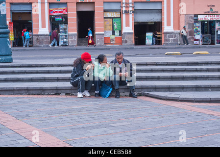 Eine dreiköpfige Familie sitzt auf Schritte auf einem Platz in Quito, Ecuador. Stockfoto