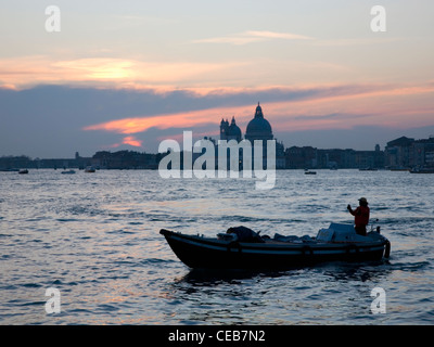 Venedig, Veneto, Italien. Blick bei Sonnenuntergang über der Lagune, die Basilica di Santa Maria della Salute, kleines Boot im Vordergrund. Stockfoto