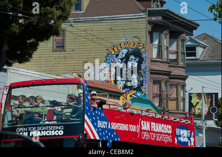 Einem oben offenen Doppel Decker Tour Bus vorbei an einem Rock Musiker Wandbild. Haight Street San Francisco. Stockfoto