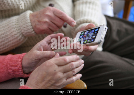 ältere ältere paar Annahme mit neuen Technologie, iPhone 4 s, Smartphone, intuitiven Touchscreen zu Hause genießen Stockfoto