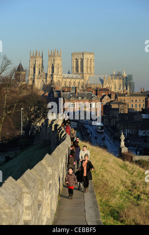 Menschen zu Fuß entlang York Stadtmauer mit York Minster im Hintergrund in der Herbstsonne Stockfoto