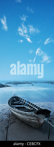 Holzboot auf dem Strand in der Dämmerung. Langzeitbelichtung geschossen, vertikales Panorama in hoher Auflösung. Stockfoto