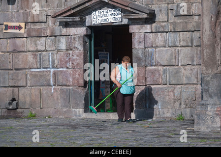 Ein Hispanic Frau Ladenbesitzer an die Kirche von San Francisco in Quito fegt den Bürgersteig außerhalb der Kirche Souvenirladen. Stockfoto