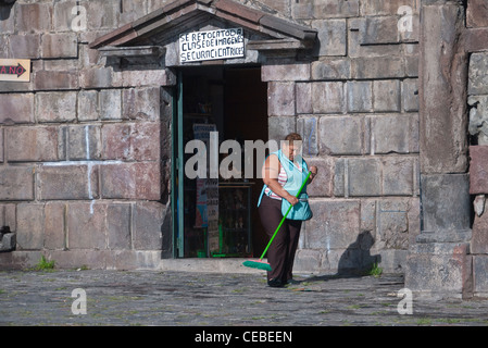 Ein Hispanic Frau Ladenbesitzer an die Kirche von San Francisco in Quito fegt den Bürgersteig außerhalb der Kirche Souvenirladen. Stockfoto