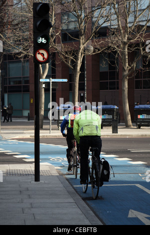 zwei Radfahrer unterwegs weitergegeben ein Zyklus Superhighway in London Ampel. Stockfoto