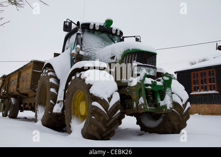 Ein grüner Traktor sitzt auf einem Hof mit Schnee bedeckt Stockfoto