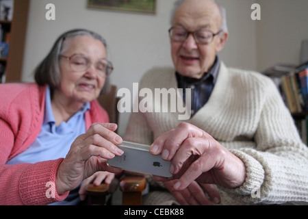 Ältere ältere paar Teilen Annahme neuen Technologie, iPhone 4, Smartphone, im Hause (Fotografen Studio) Leiston, Suffolk, UK. Stockfoto