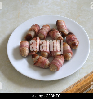 Eine Auswahl von Schweinen in Decken (Würstchen, Speck umwickelt) auf einer weißen Platte Stockfoto