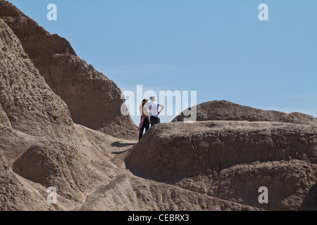 Zwei junge Männer, die auf den felsigen Bergen stehen, sehen die Landschaft des American National Park South Dakota in den USA in flachem Winkel von unterhalb der horizontalen Hi-res Stockfoto