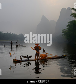 Kormoran Fischer paddeln Bambus Flöße im Morgengrauen auf dem Li-Fluss mit Karst Berggipfeln Xingpingzhen Yangshuo, Guilin, Guangxi, China Stockfoto