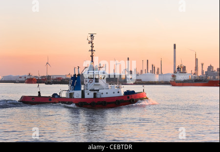 Schlepper an farbenprächtigen Sonnenuntergang mit hoher Geschwindigkeit auf dem Fluss vorbei - Verschmutzung durch die Industrie ist den Himmel Malerei Stockfoto