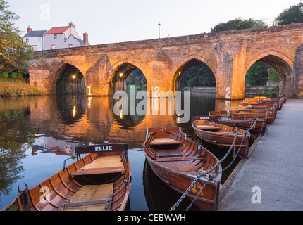 Elvet Brücke über den Fluss zu tragen, mit Reflexion und Vergnügen Ruderboote zu mieten vertäut am Ufer Flusses in Durham, England Stockfoto