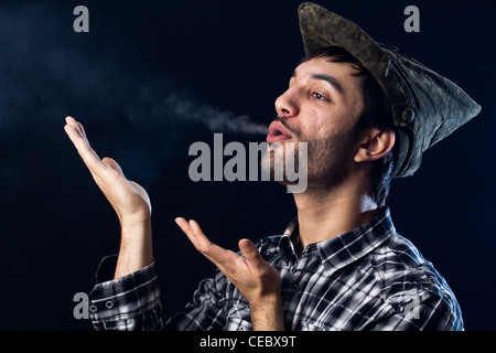 Mann auf schwarzem bläst Rauch in Richtung Kamera nach links Stockfoto