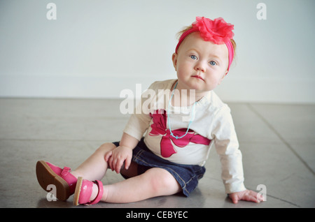 Baby/Kleinkind sitzen am Boden im Studioumgebung.  Sie ist niedlich, roter Kopf und starrte auf die Kamera. Stockfoto